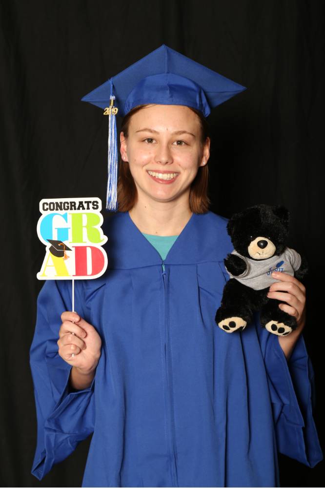 person holding graduate prop and stuffed bear
